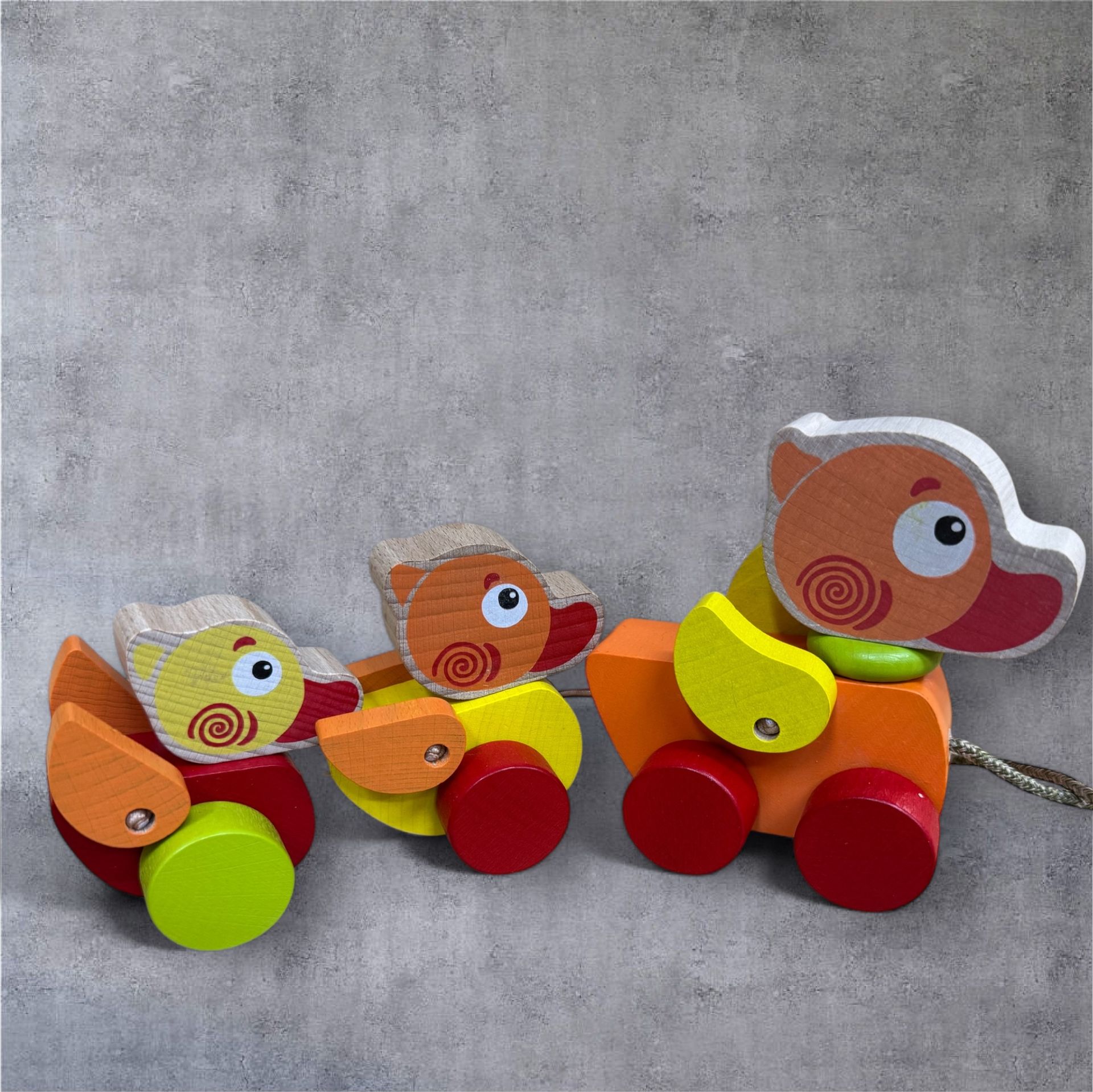 Three wooden ducks are pulled by a string