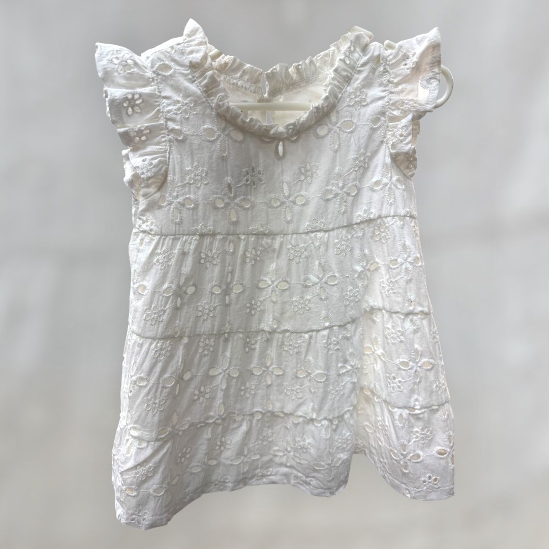 A white lace dress with ruffled sleeves is hanging on a hanger.