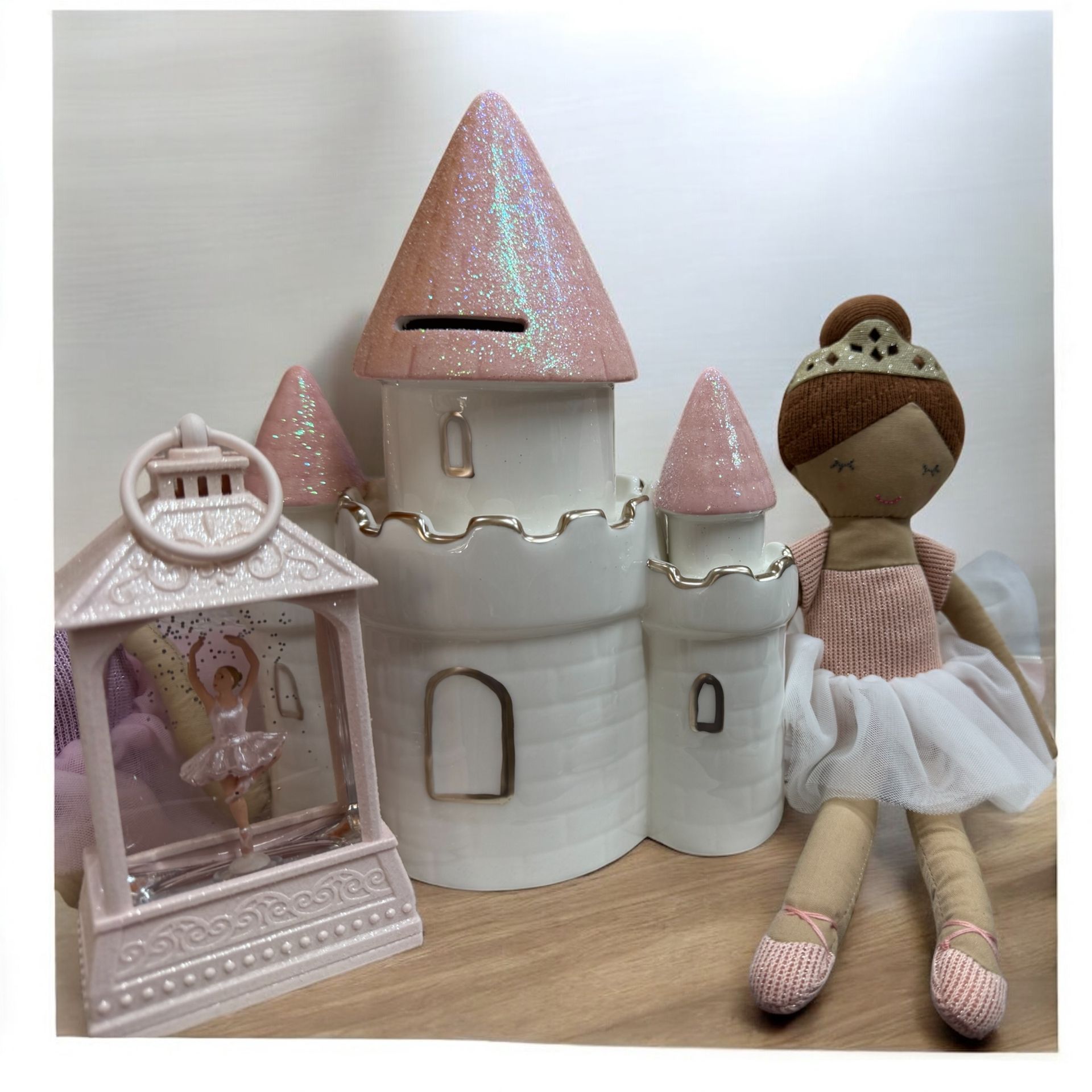 A ballerina doll is sitting in front of a pink castle