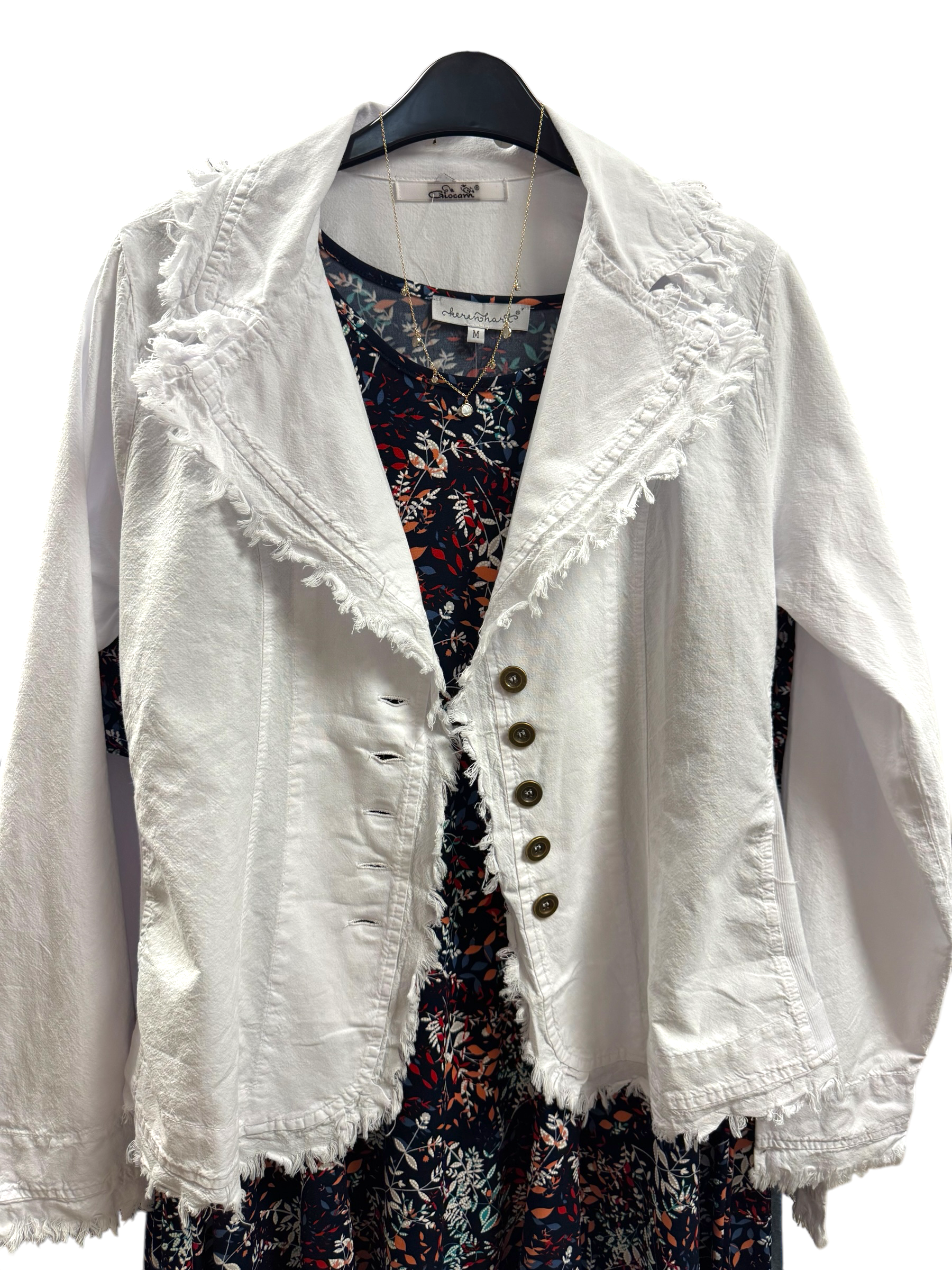 A white jacket is hanging on a hanger next to a dress.