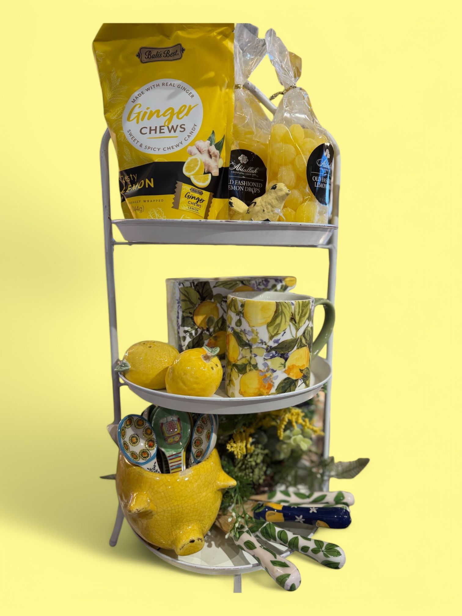 A three tiered display filled with lemons , mugs , and candy.