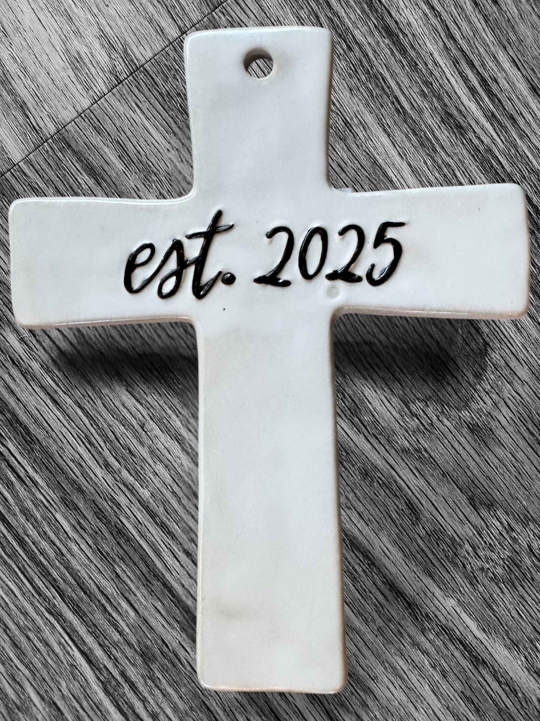 A white cross with the year 2025 on it is sitting on a wooden table.