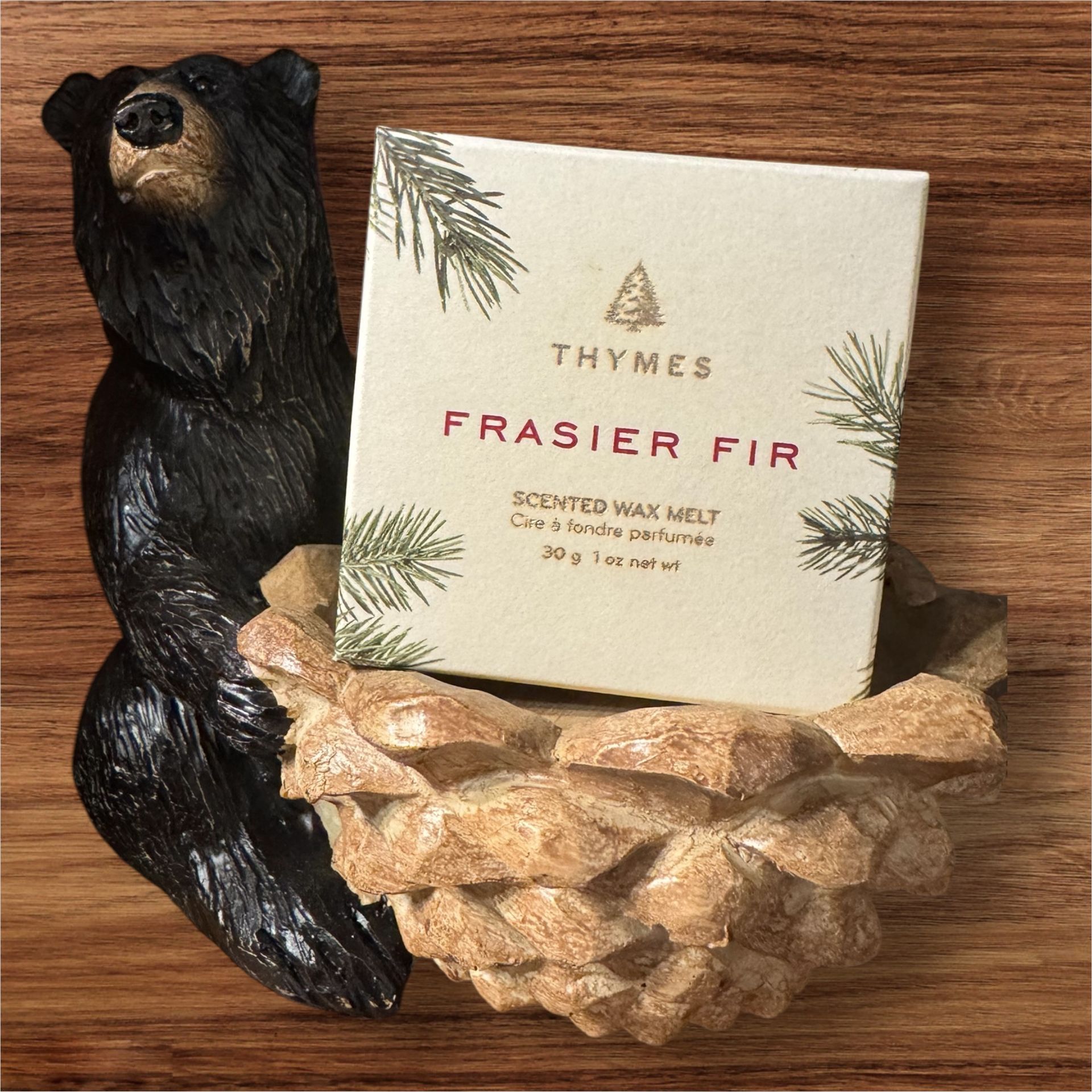 A black bear is sitting next to a box of thymes frasier fir wax
