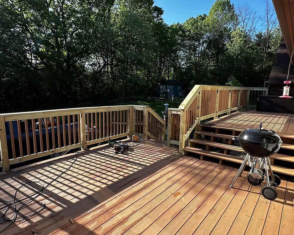 A wooden deck with stairs and a grill on it.