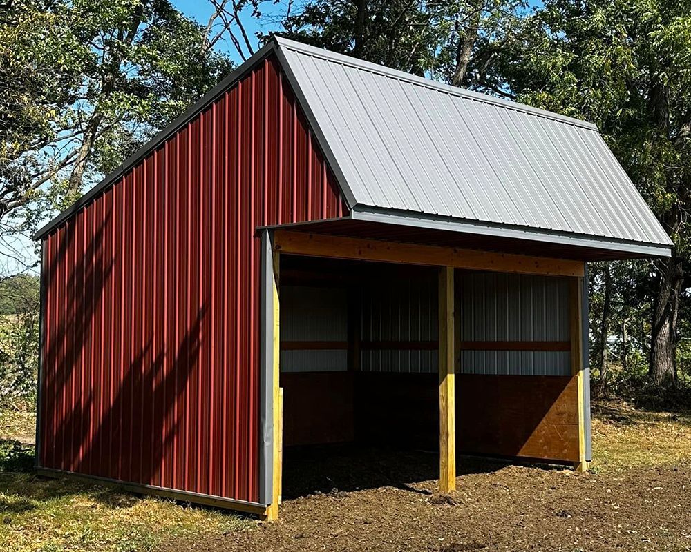 A red barn with a white roof is in the middle of a field