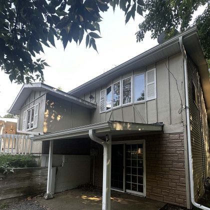 The back of a house with a porch and a lot of windows.