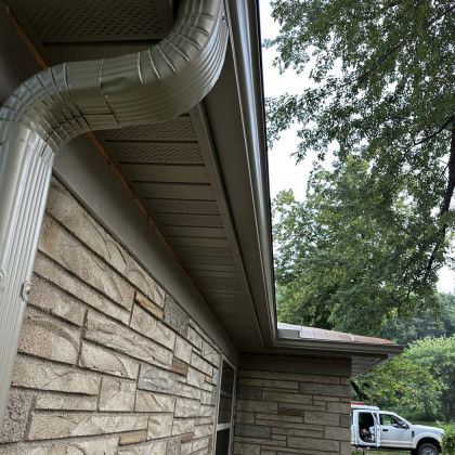 A white truck is parked on the side of a house next to a gutter.