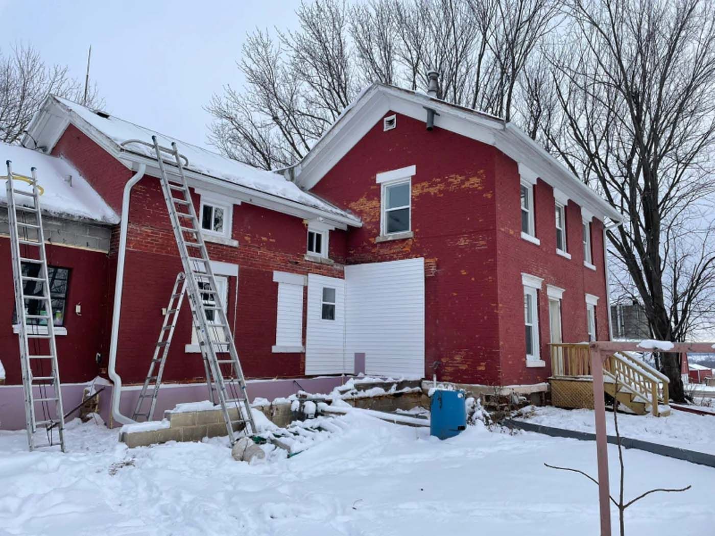 A red house is being painted in the snow.