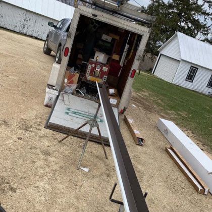 A truck is parked in a dirt field next to a building.