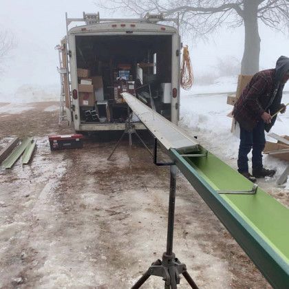 A man is standing in front of a trailer in the snow.