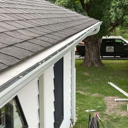 A white house with a gutter on the side of it.