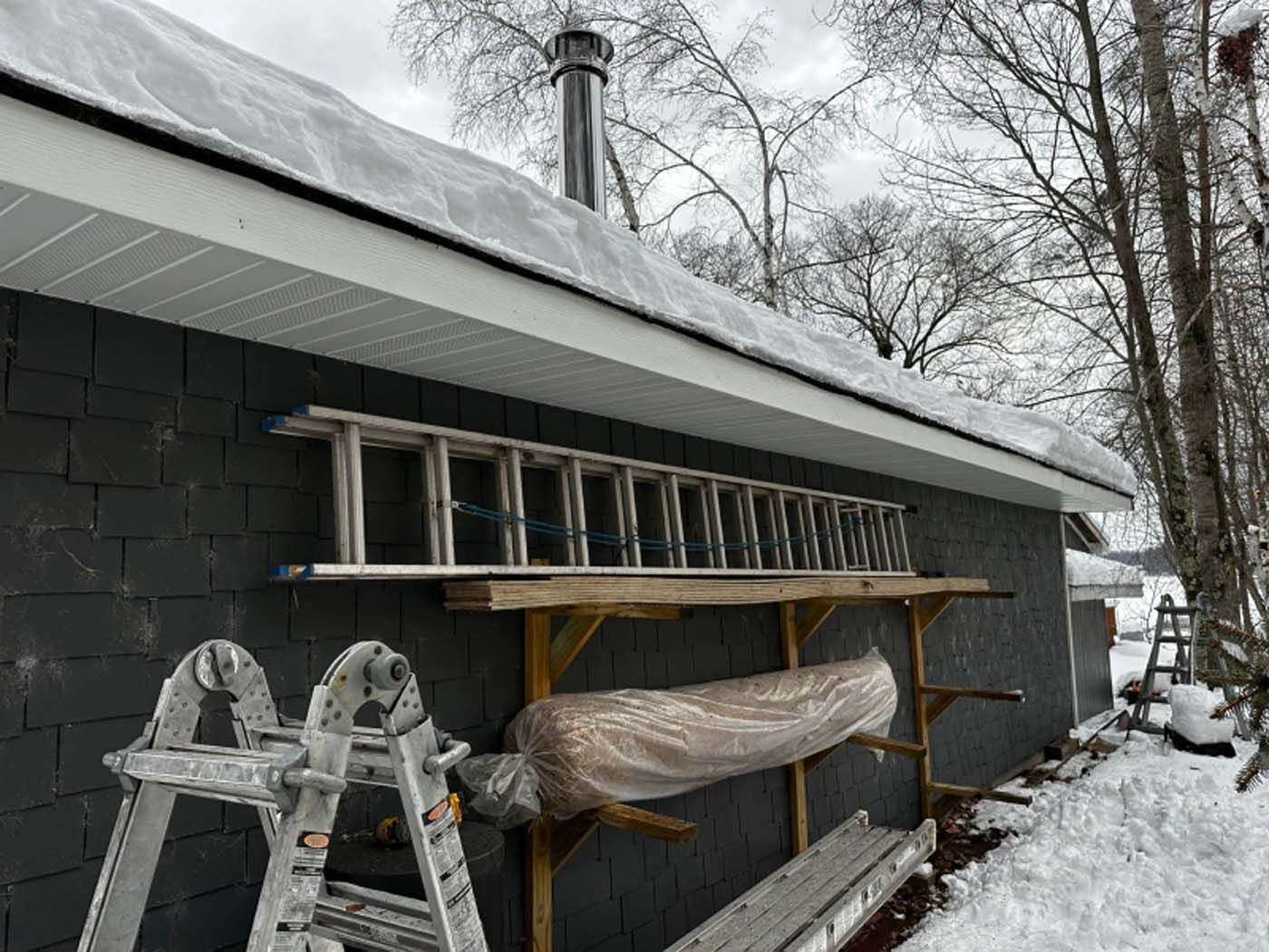 A ladder is sitting on a wooden rack on the side of a building.