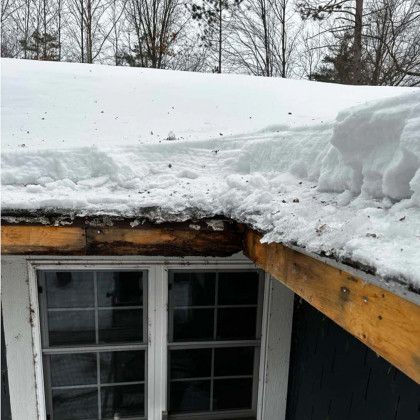 There is a lot of snow on the roof of a house.
