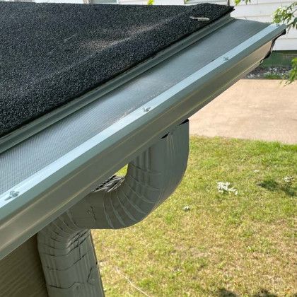 A close up of a gutter on a house with a black roof.