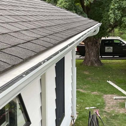 A white house with a gutter on the side of it.