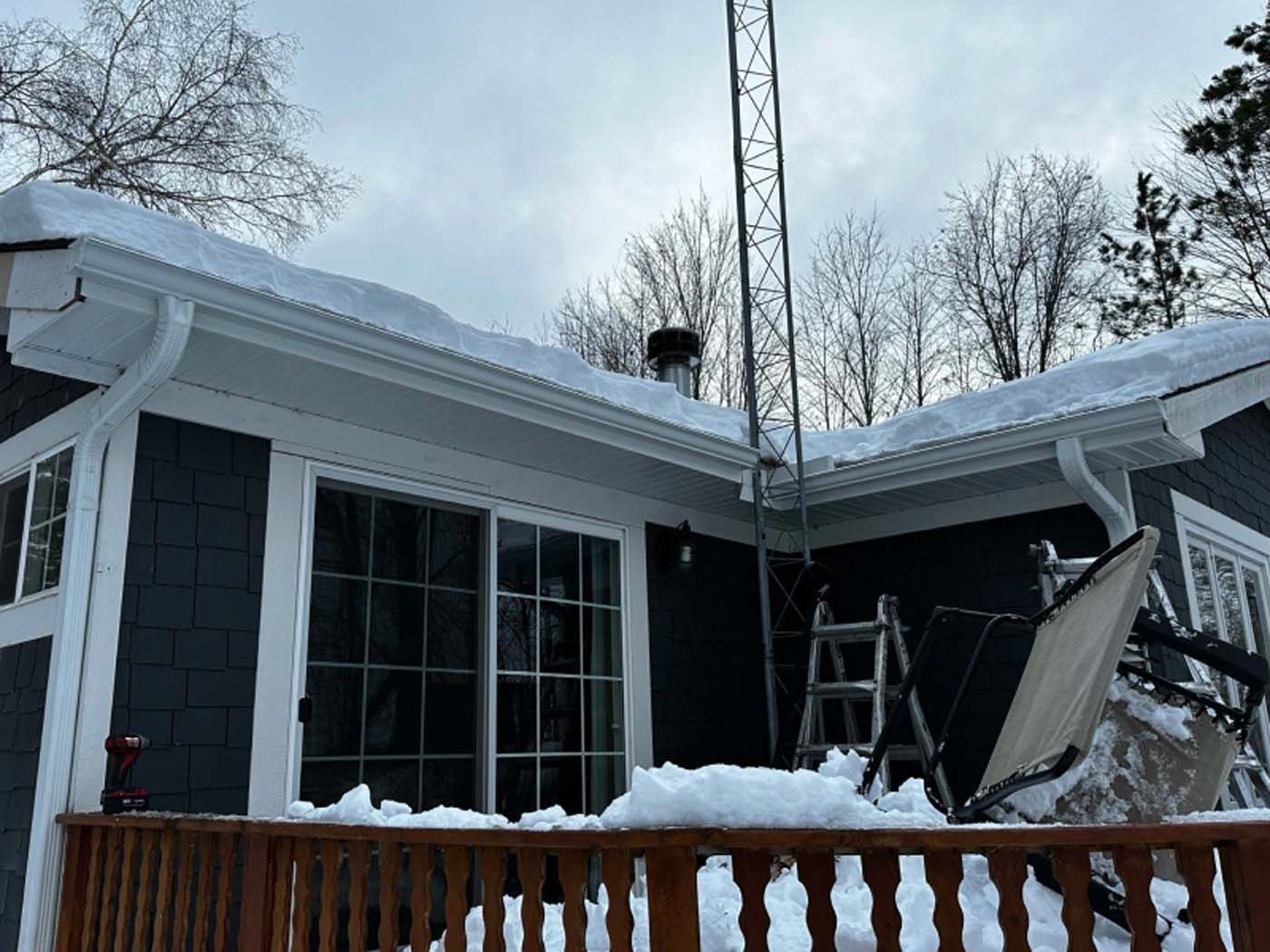 A house with snow on the roof and a wooden deck.