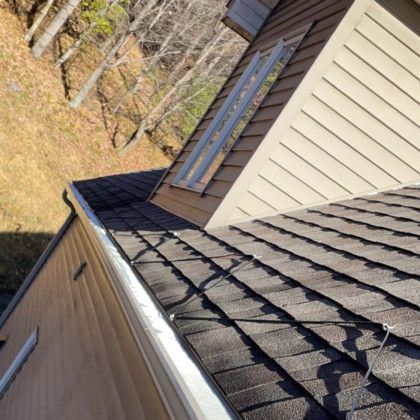 A roof of a house with a gutter and a window.