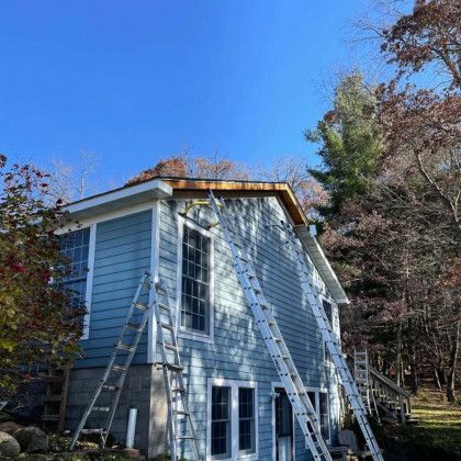 A house with a ladder on the side of it is being painted.