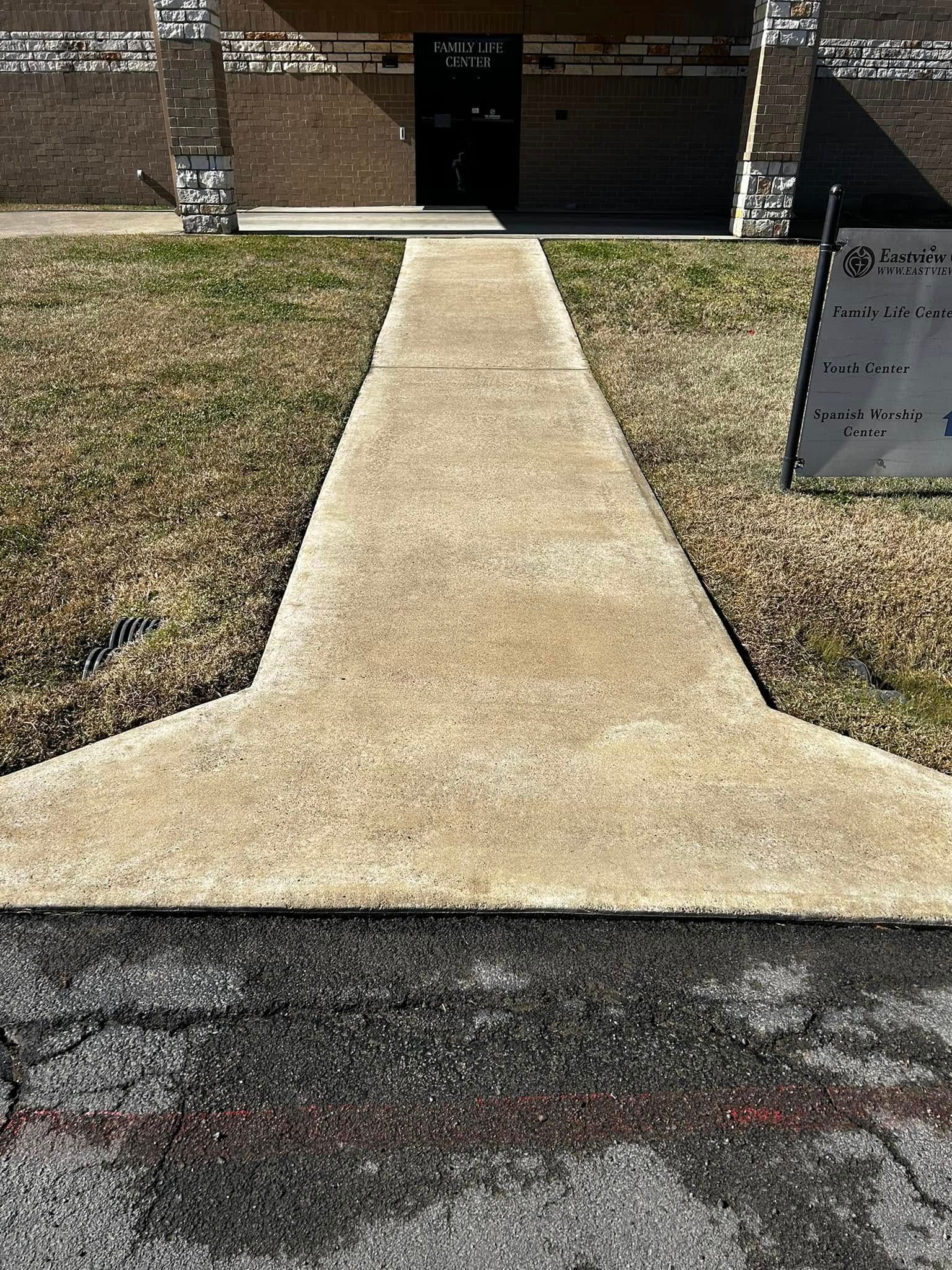Concrete walkway leading to a building entrance. Sidewalk has a concrete extension.
