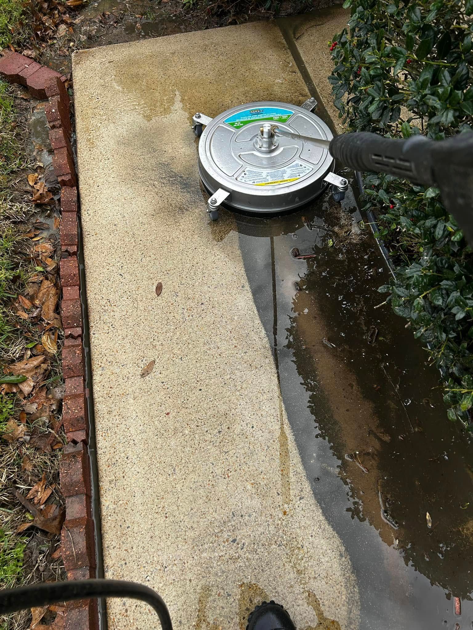 Power washer cleaning a concrete walkway. Wet path contrasted with the dirty.