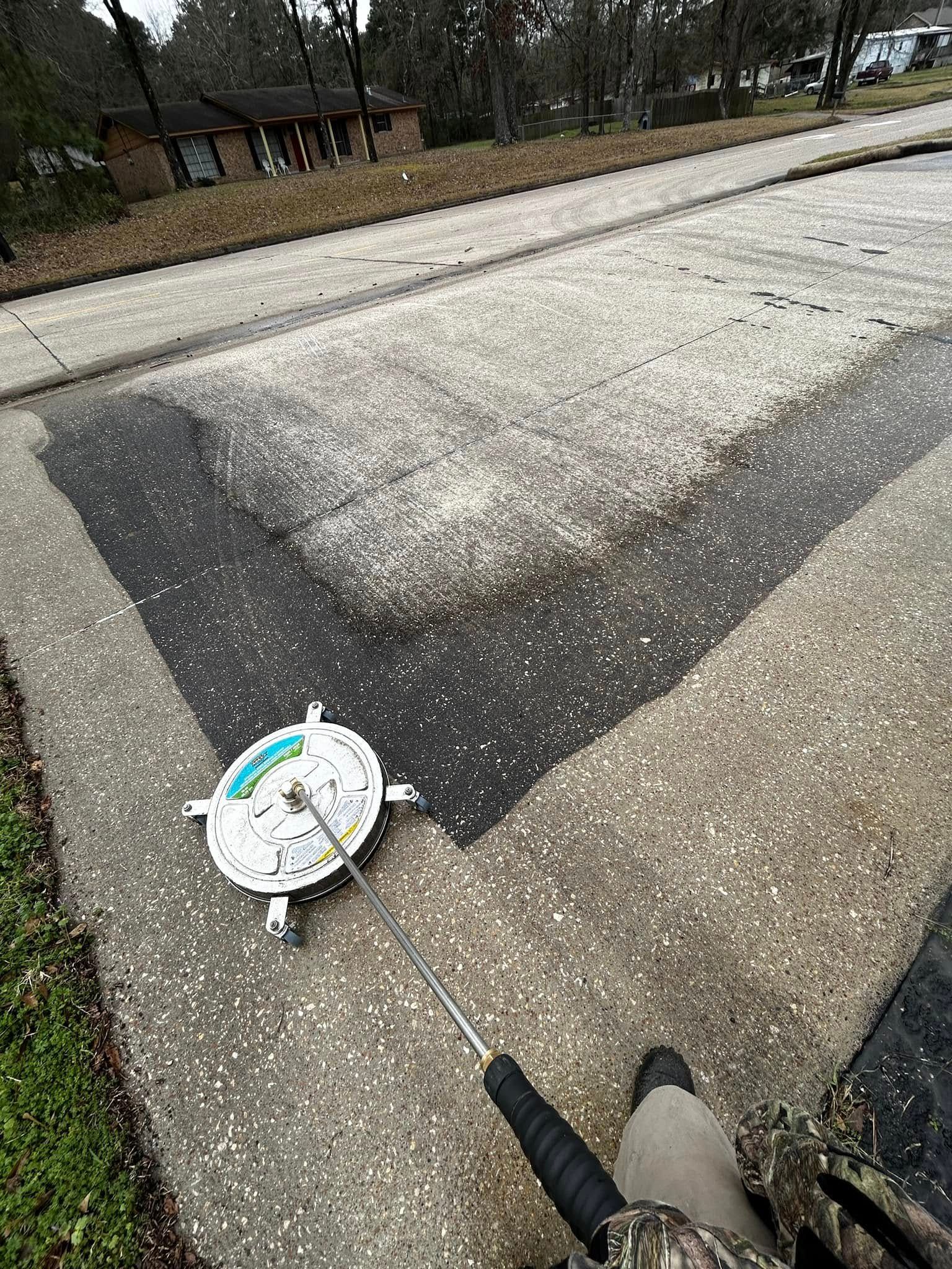 A person pressure washes a concrete surface. The cleaned section is visible with a pressure washer in view.