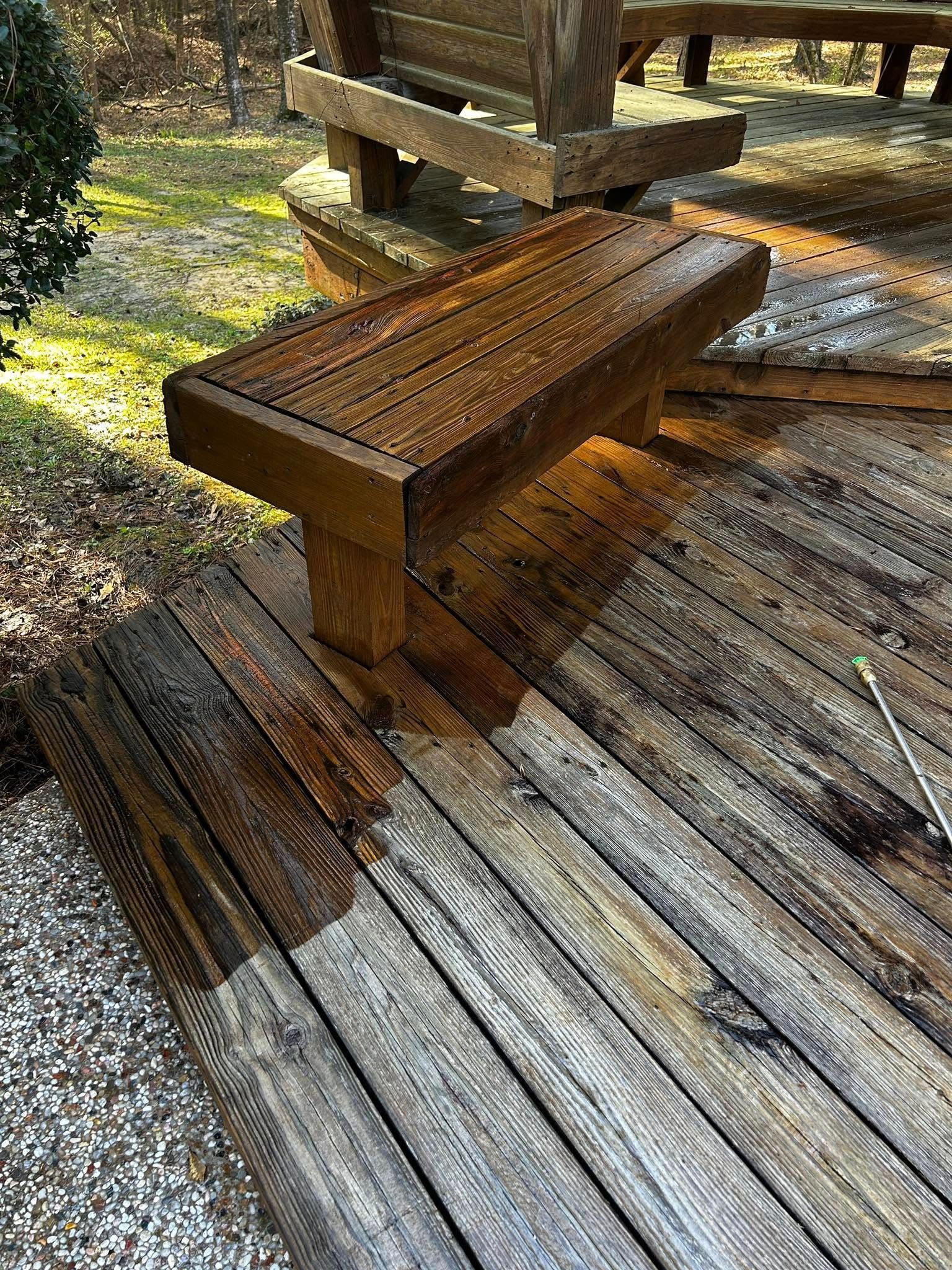 Wet wooden deck and bench in a backyard setting, possibly after cleaning.