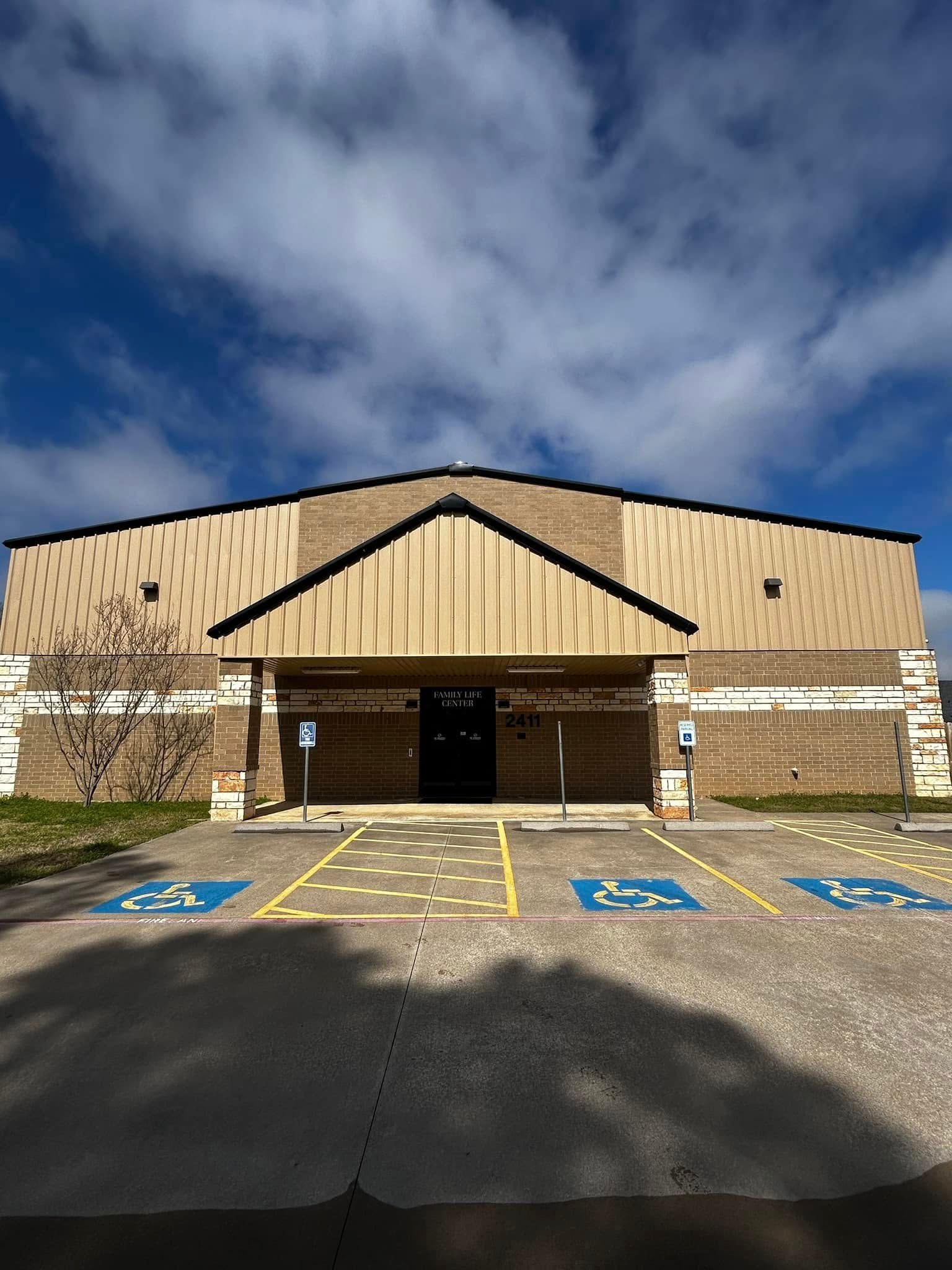 A building with brown brick facade, accessible parking, and blue sky.