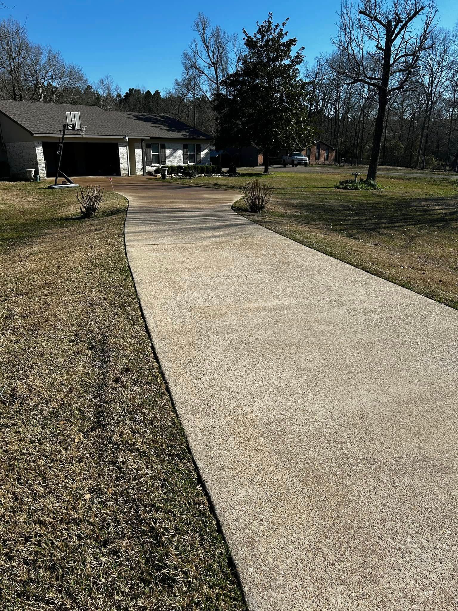 A concrete driveway leads to a one-story house with a garage on a sunny day.