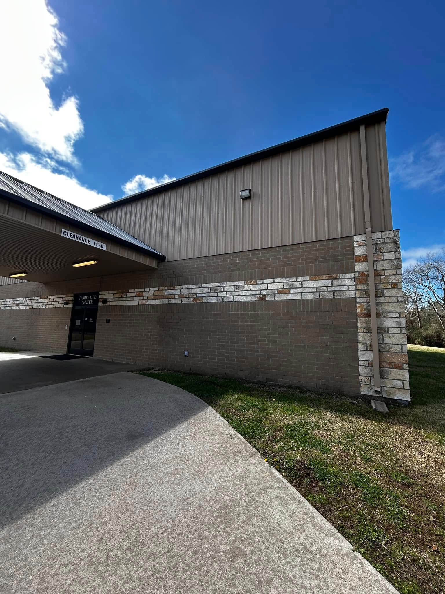 Exterior of a building with a textured brick and metal exterior, under a blue sky.