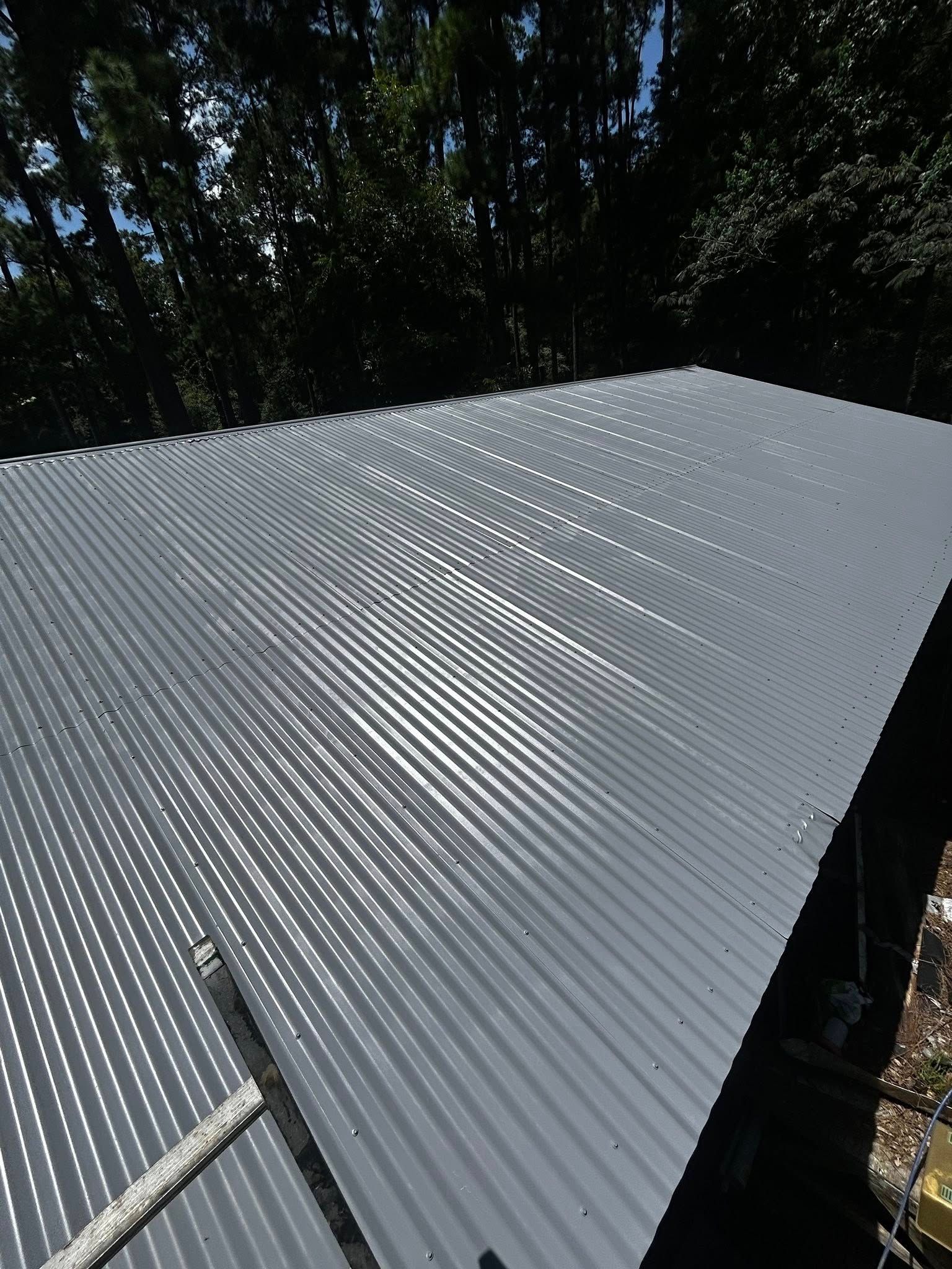 Gray corrugated metal roof with trees in the background.