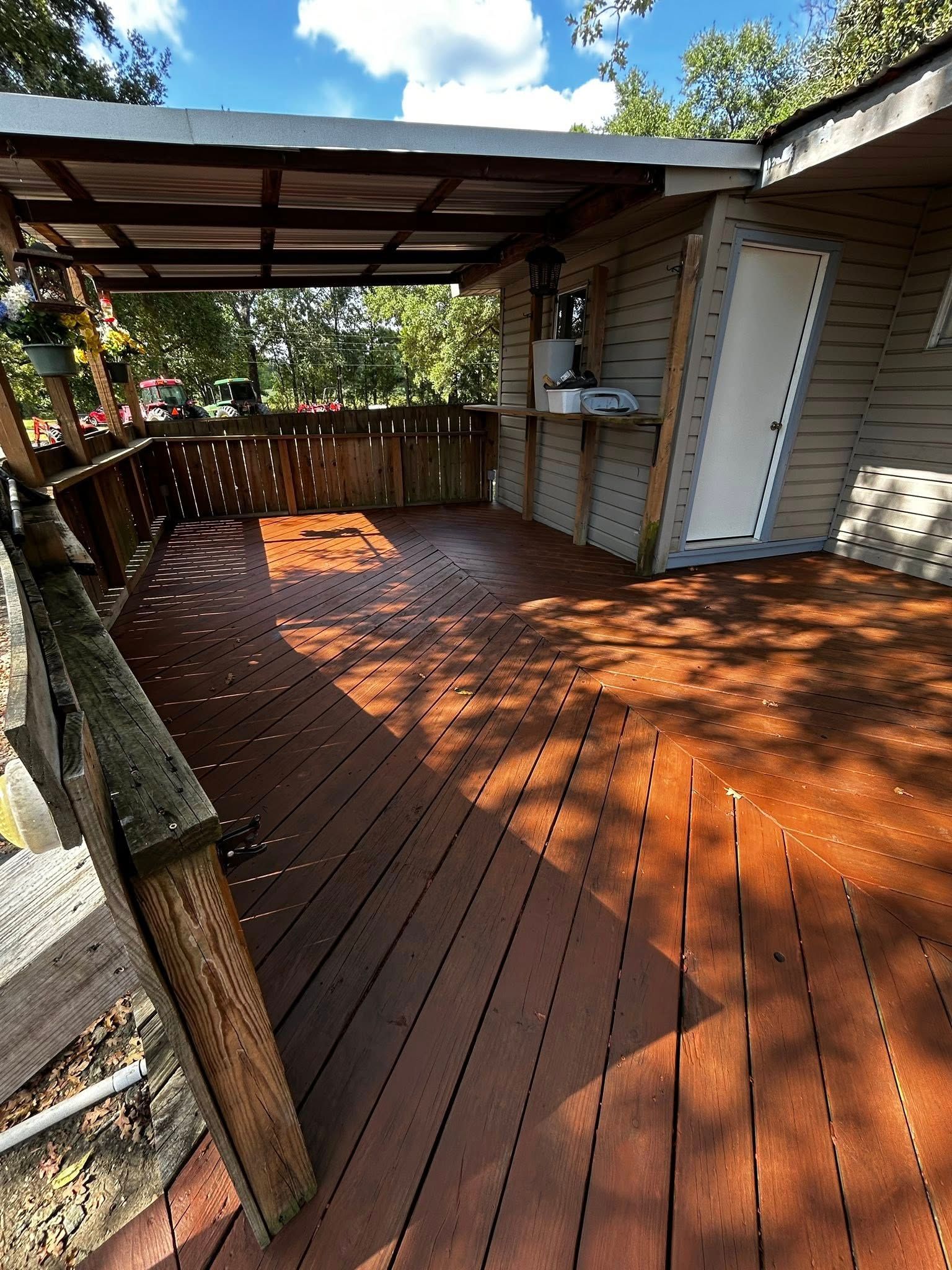 Wooden deck with partial canopy, door, and railing on a sunny day.