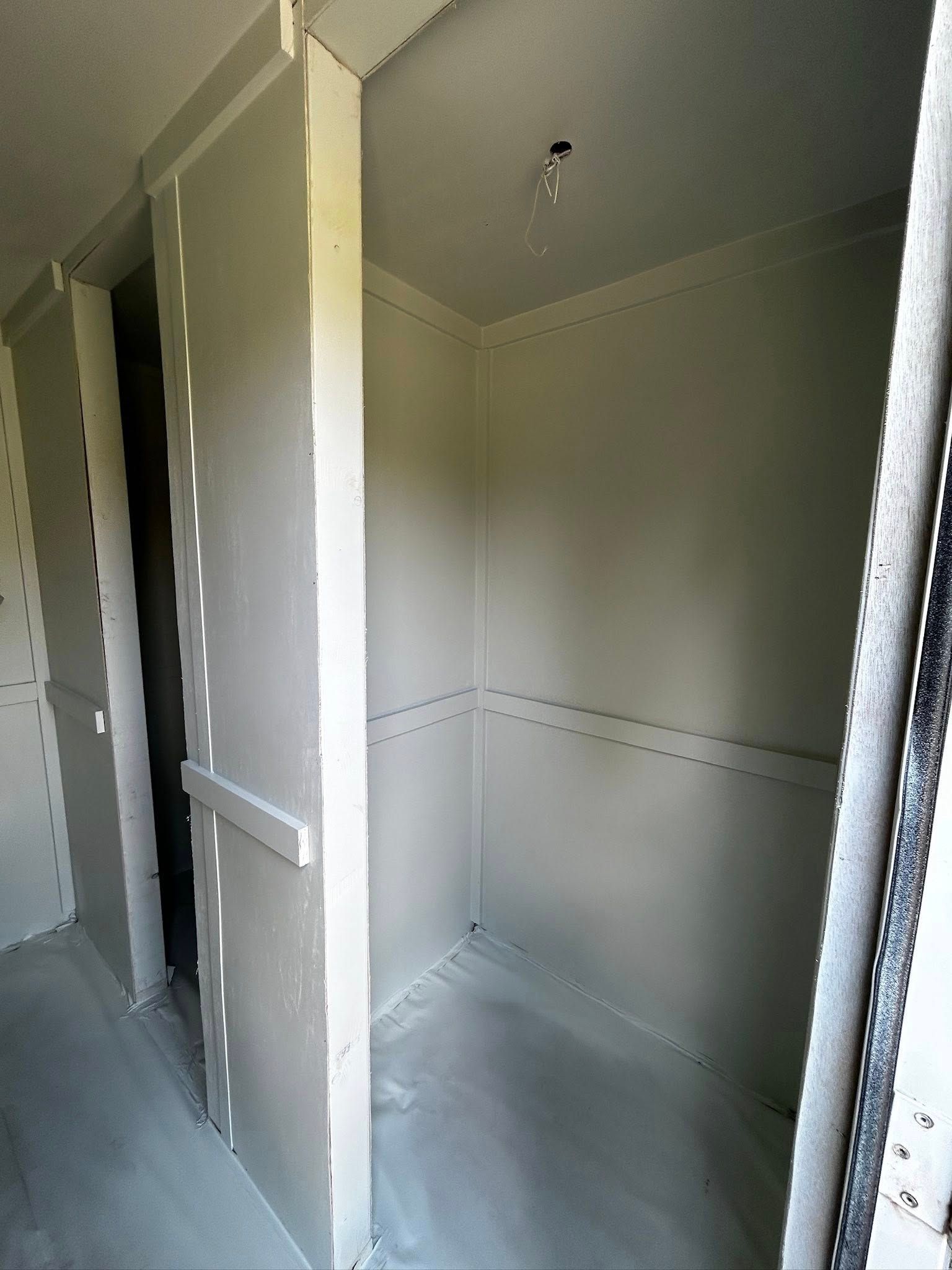 An unfinished interior closet with white walls and a gray floor.