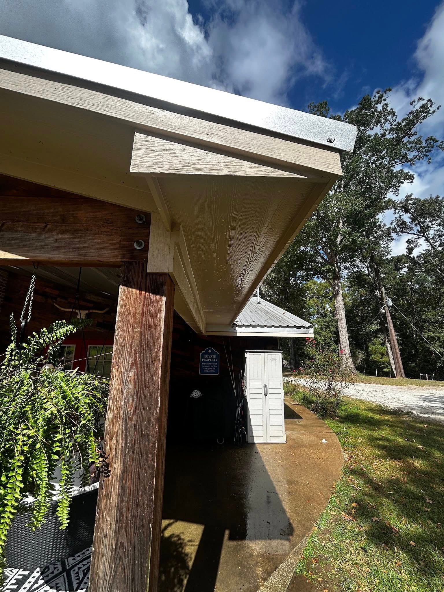 Covered walkway with a concrete beam, wood post, and greenery on a sunny day.