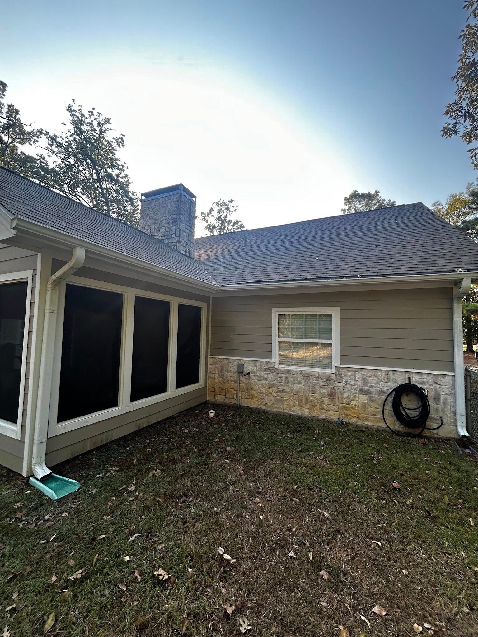 Exterior of house with screened porch, chimney, beige siding, and green lawn.