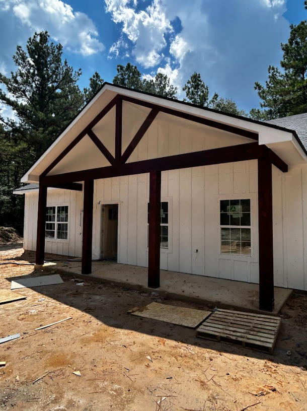 New house under construction with white siding, dark brown posts and accents, and a covered porch.