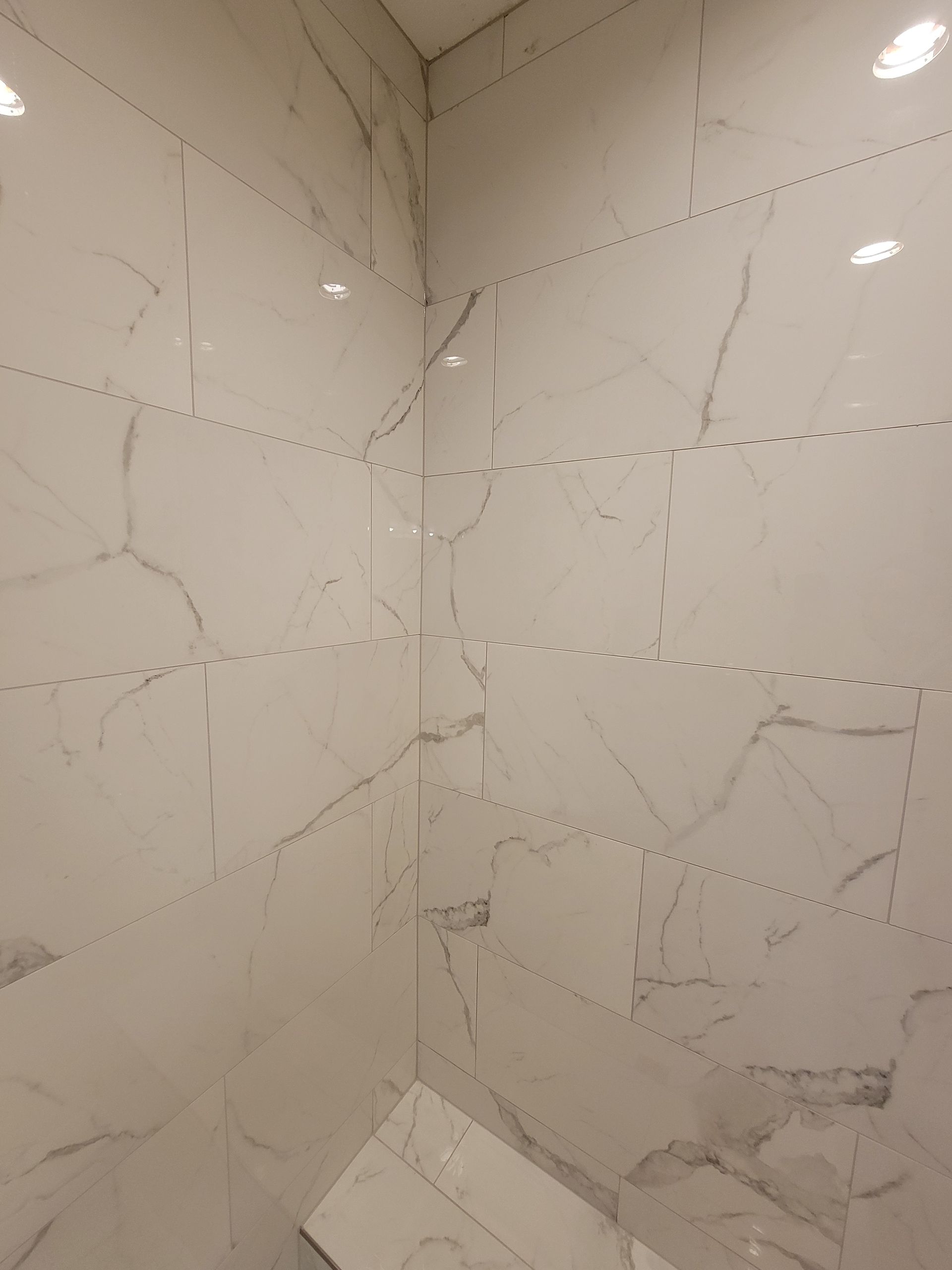 White marble tile bathroom walls with dark grout lines.