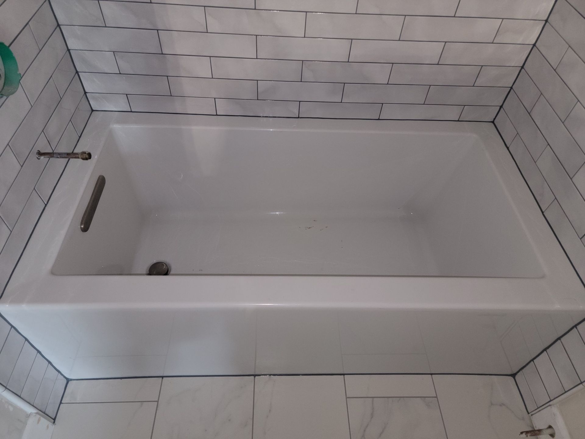 White bathtub with gray subway tile surround.