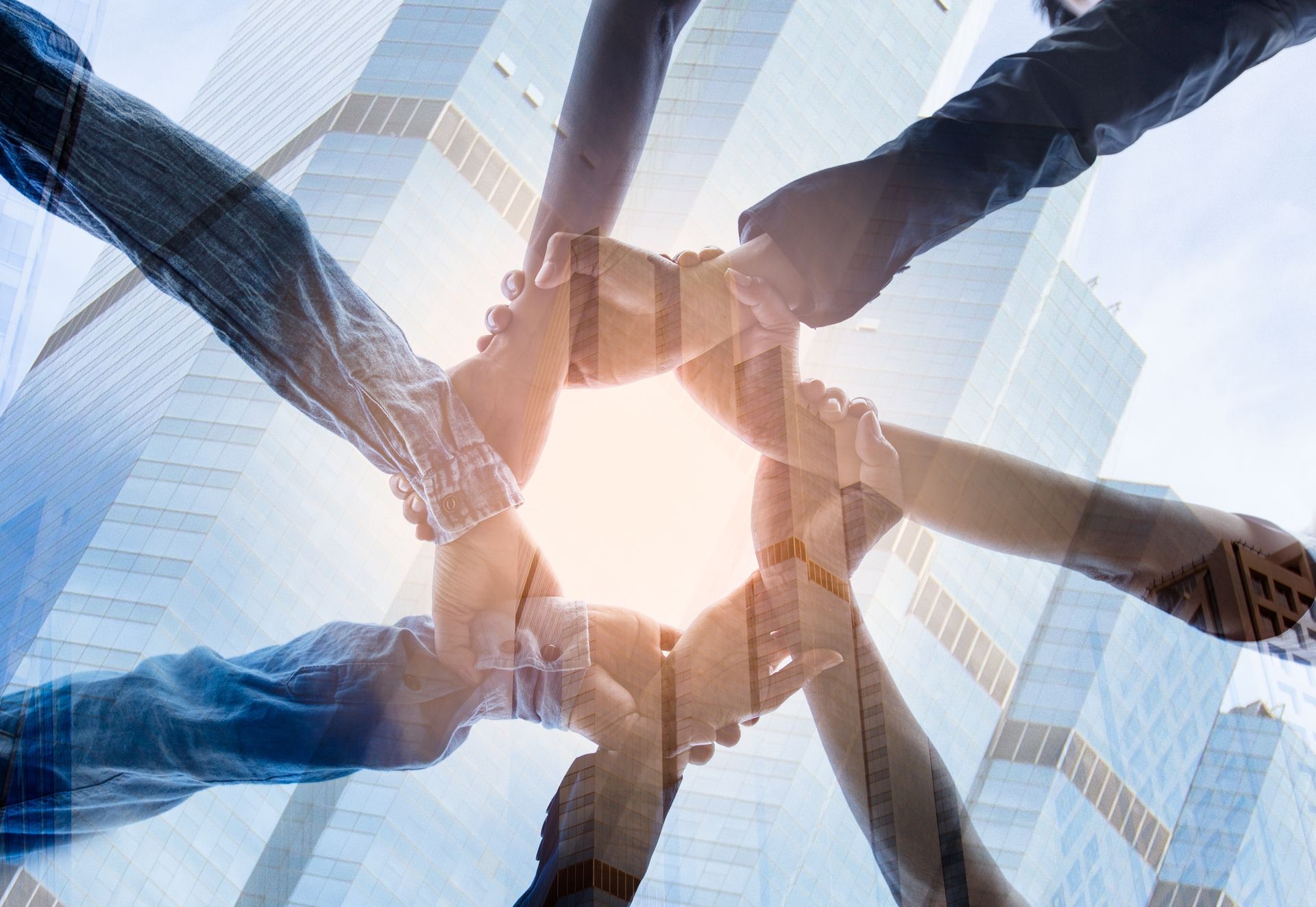 A group of people are putting their hands together, symbolizing coming together through local marketing for small businesses.