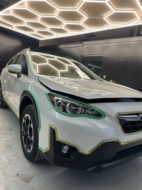 A white car is sitting in a garage under a honeycomb ceiling.
