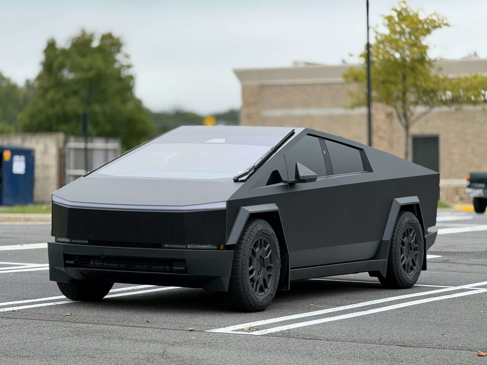Black Tesla Cybertruck parked in a parking lot, futuristic design.