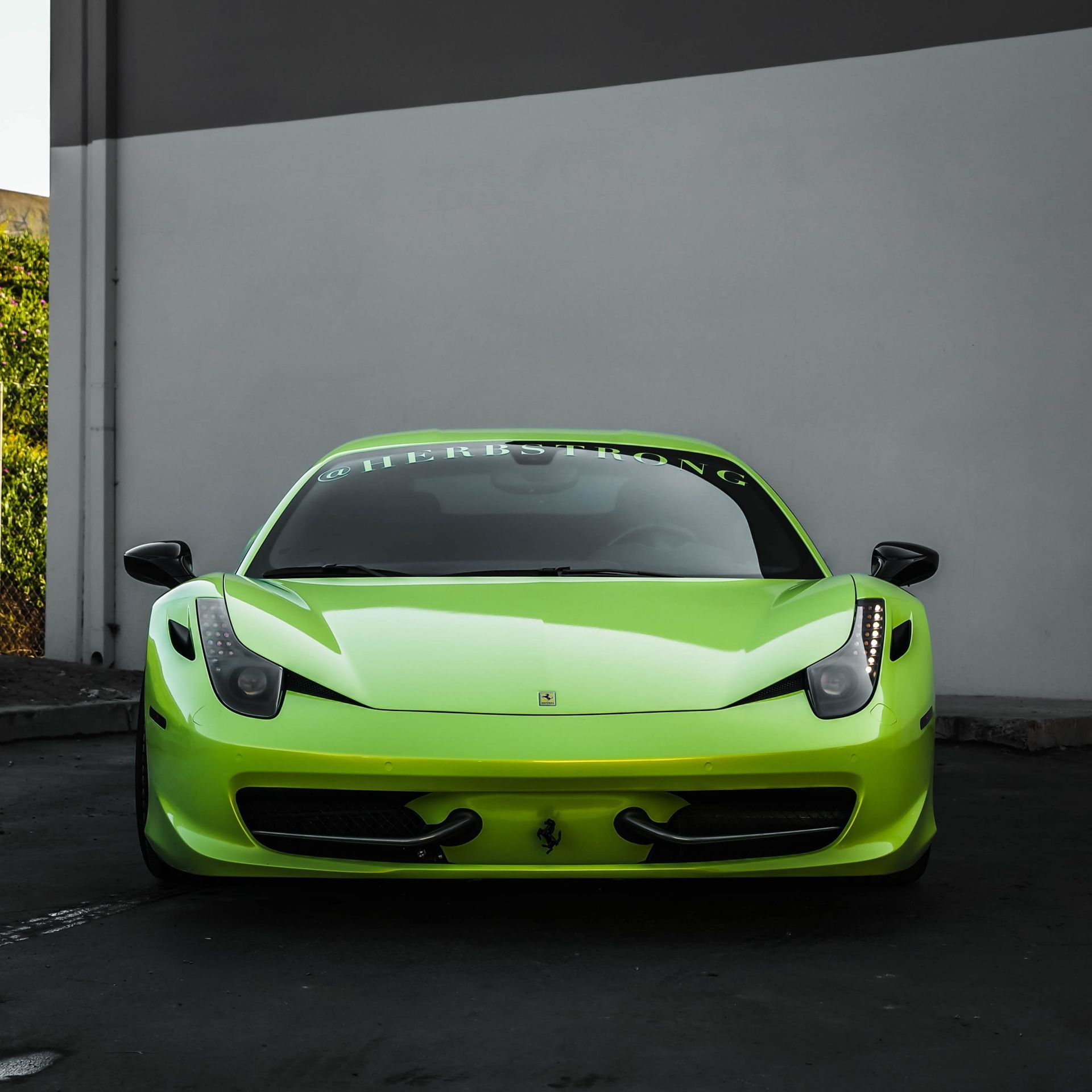 A bright green sports car is parked in front of a building