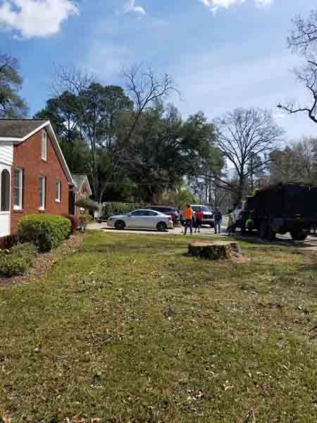 A group of people are standing in front of a brick house.