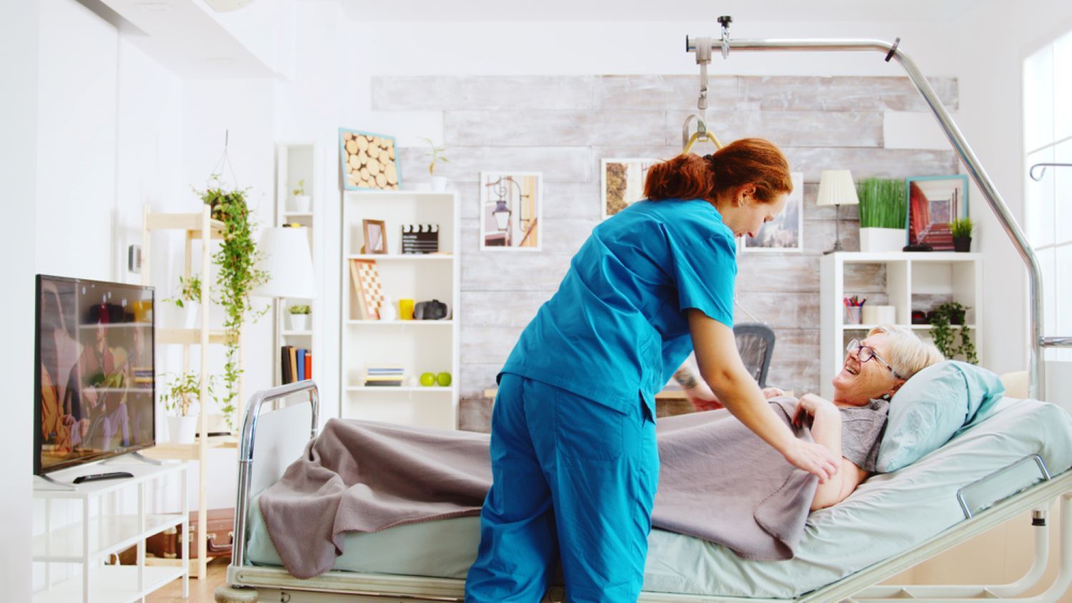 A Nurse is Standing Next to an Elderly Woman in a Hospital Bed — Supportability Care Services in West Rockhampton, QLD