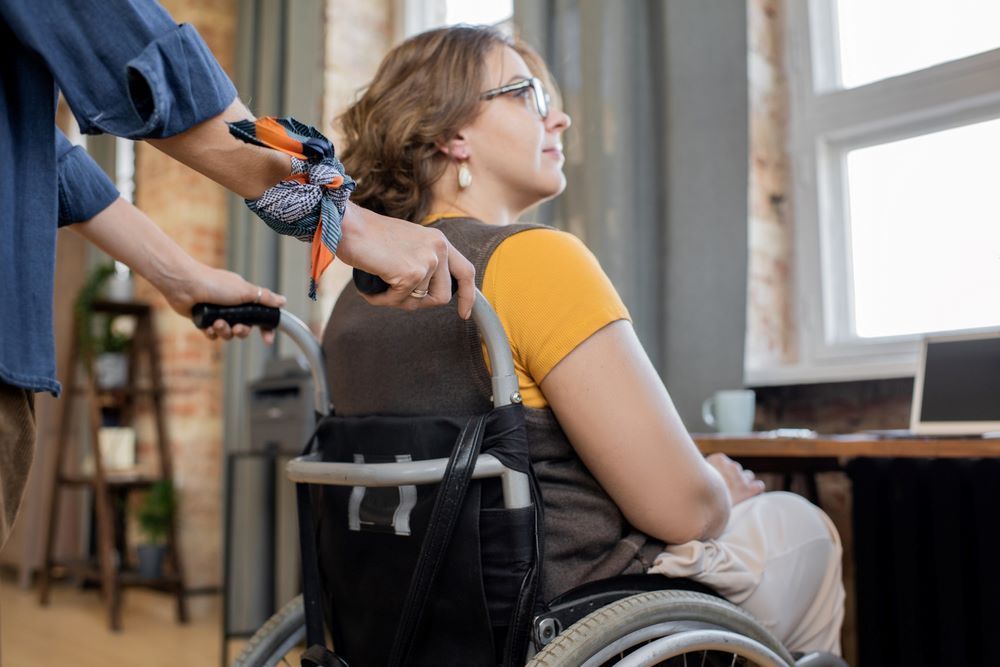 A Woman in a Wheelchair is Being Helped — Supportability Care Services in West Rockhampton, QLD