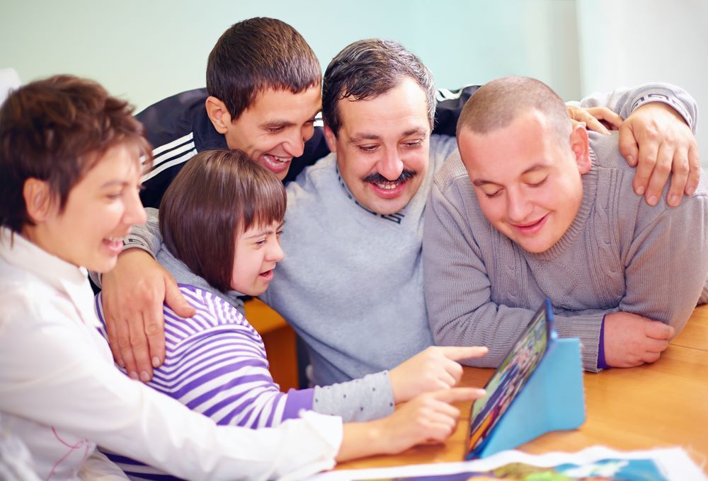 A Group of People Are Looking at a Tablet Together — Supportability Care Services in West Rockhampton, QLD