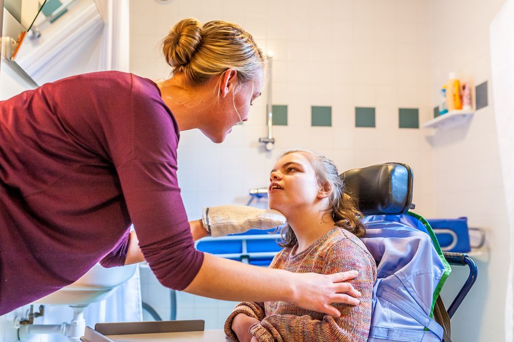 A Woman is Feeding a Child in a Wheelchair — Supportability Care Services in West Rockhampton, QLD