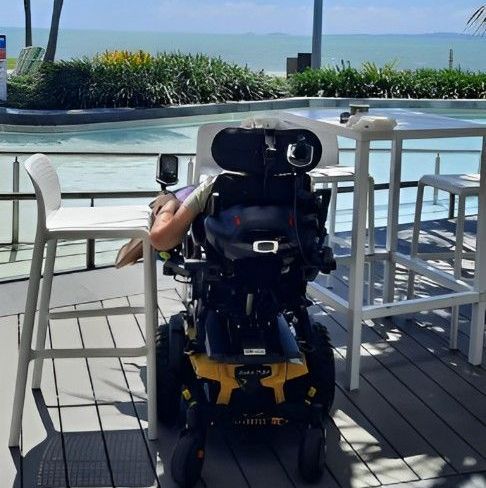 A Person in a Wheelchair is Sitting Next to a Pool — Supportability Care Services in West Rockhampton, QLD