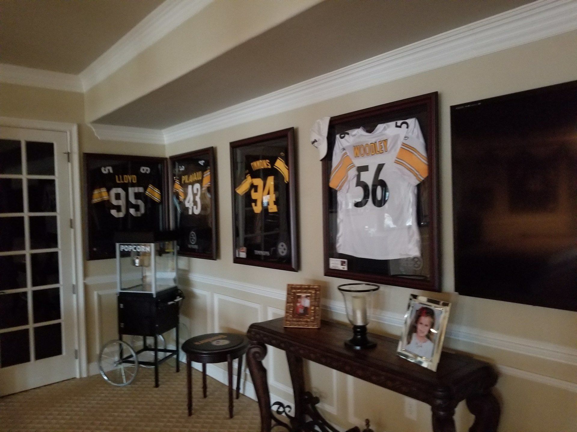NFL jerseys framed on the wall, Steelers colors, with a popcorn machine and table.