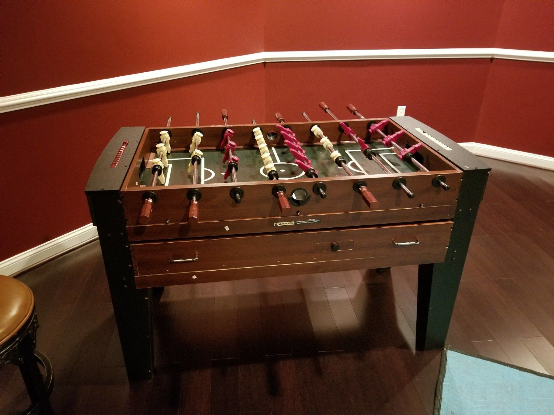 Foosball table in a room with red walls and a dark wood floor.