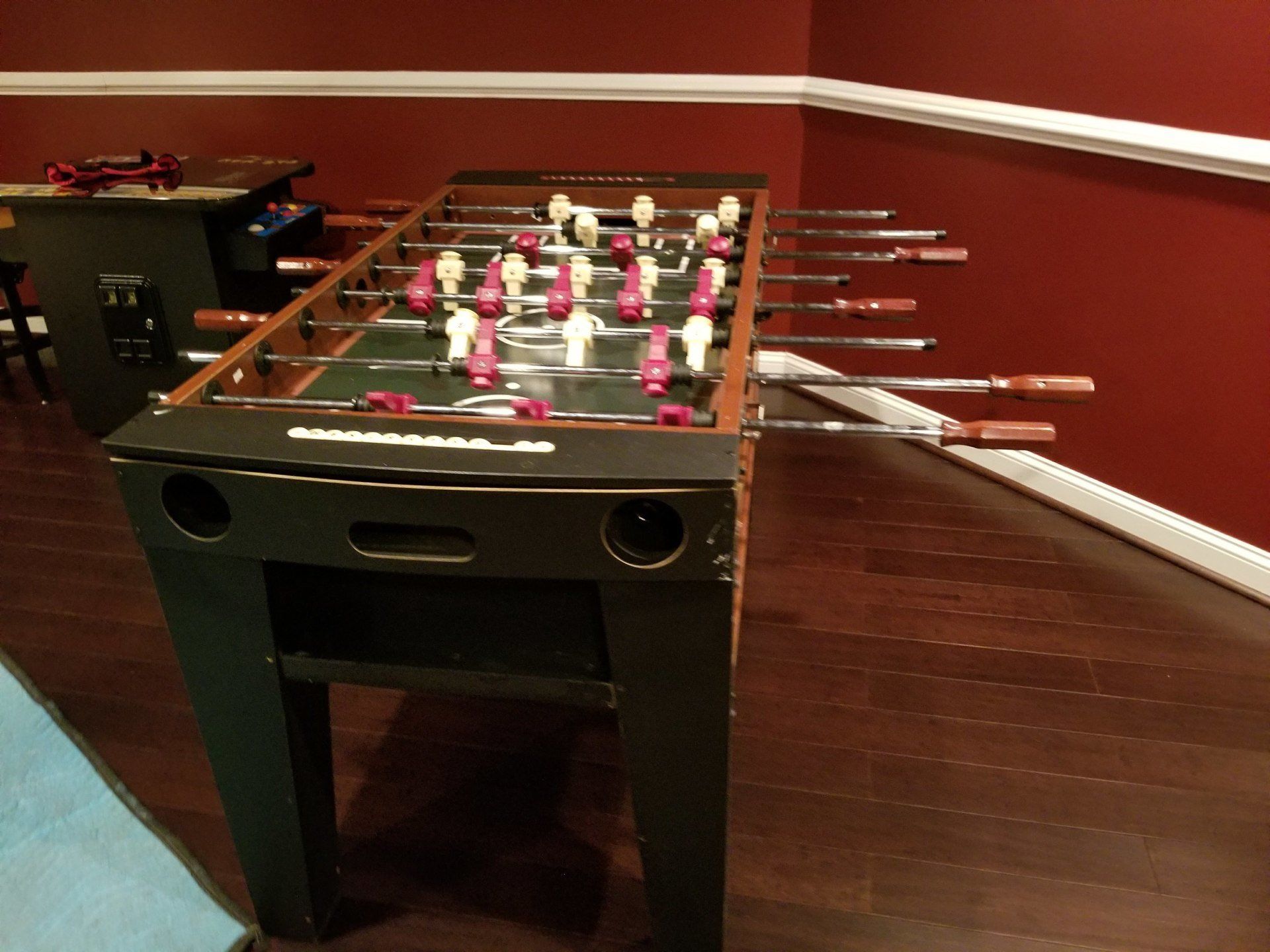 Foosball table in a room with red walls and hardwood floors.
